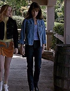 two young women walking down a sidewalk next to each other with wine barrels in the background