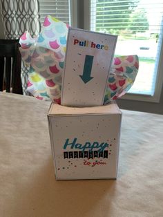 an open box sitting on top of a table next to a balloon filled with confetti