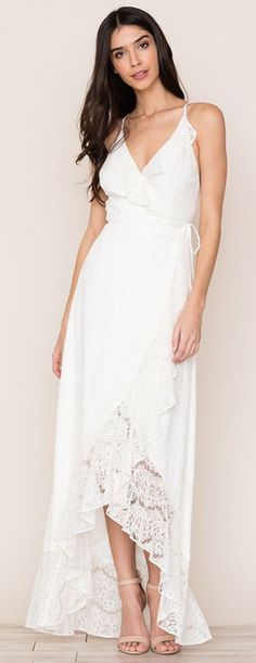 a woman is wearing a white dress with lace on the bottom and one side,