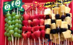 fruit skewers are arranged in the shape of batman's and green apples