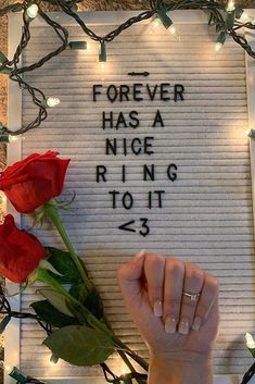 a person holding a rose in front of a sign that says forever has a nice ring to it