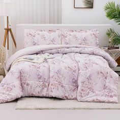 the comforter is made up with pink flowers on it and white rugs in front