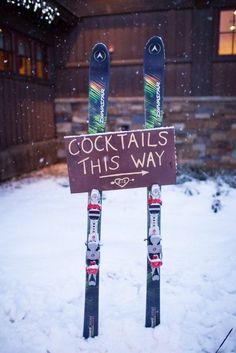 two skis are propped up in front of a sign that says cocktails this way