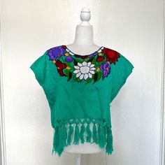 Very beautiful handmade Mexican Huipil Embroidered blouse. Great for the summer, they are very light and comfortable. Made In Mexico By: Mexican Artisans For: Women Size: M/L (view size chart) Color: teal | multi Details: - Material: Cotton - Non-stretch - Embroidery thread - Pullover closure - Boat neckline - Tassels on end Washing Instructions: One thing to remember when you wash a shirt, is to wash them with similar colors, and to use cold or warm water. A gentle detergent is always recommended as well. If you are concerned about damaging your shirt, send it to a dry cleaner to clean. Drying Instructions: If you need to dry your shirts with a dryer, always option for low heat or no heat. To prevent your shirt from shrinking, the recommended way to dry your shirt is to air dry it. If pos Summer Beach Blouse With Crew Neck, Summer Crew Neck Blouse For Beach, Summer Crew Neck Blouse For The Beach, Floral Print Crew Neck Blouse For Beach, Spring Cotton Free Size Tops, Cotton Tops Free Size For Spring, Bohemian Crew Neck Top With Geometric Embroidery, Green Embroidered Crew Neck Blouse, Summer Blouse With Floral Embroidery And Short Sleeves