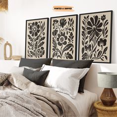 two black and white paintings on the wall above a bed