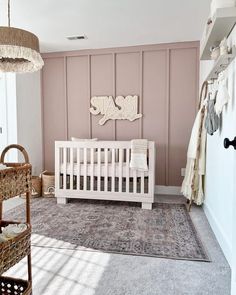 a baby's room with pink walls and white crib in the corner, along with wicker baskets on the floor