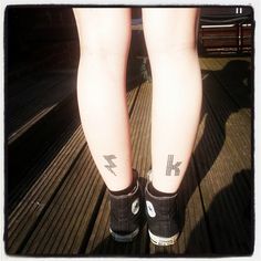 a person with tattoos on their legs standing on a wooden floor next to a bench