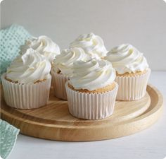 cupcakes with white frosting on a wooden plate