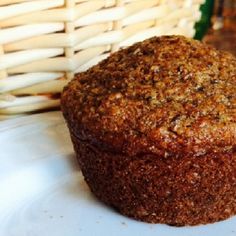 a muffin sitting on top of a white plate next to a wicker basket