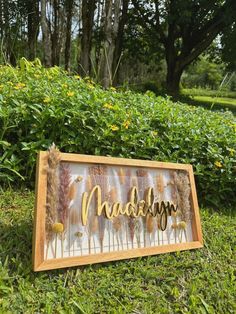 a wooden sign that says naddelin on it in front of some bushes and flowers