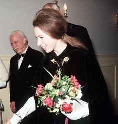 a woman in a black dress holding a bouquet of flowers