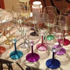 several wine glasses are lined up on a table with glittered stemware in the middle