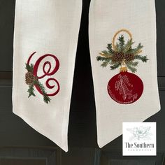 two christmas decorations are hanging on the front door with white linens and red ornament