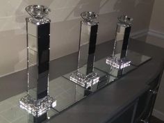 three crystal candlesticks are sitting on a glass shelf in front of a wall