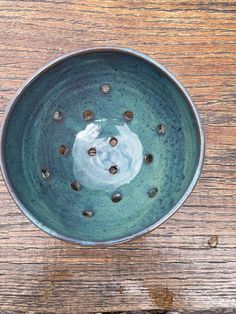 a blue bowl with holes in it on a wooden table