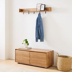 a coat rack with two coats hanging on it next to a basket and potted plant