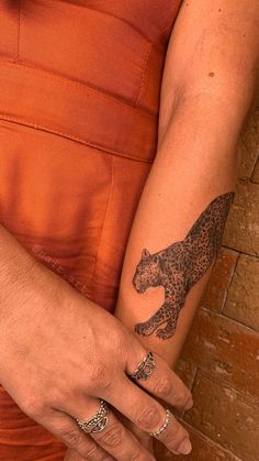 a woman's arm with a cheetah tattoo on it, and an orange dress