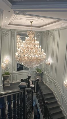 a chandelier hanging from the ceiling in a room with stairs and railings