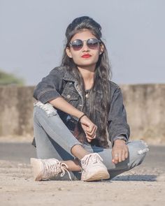 a woman sitting on the ground wearing sunglasses