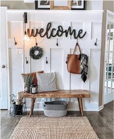 a wooden bench sitting in front of a white wall with a welcome sign on it