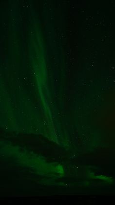 the sky is filled with green and white aurora bores in the distance, as well as stars