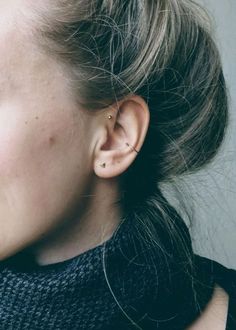 a close up of a person with ear piercings on their ears and wearing a black sweater