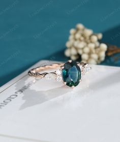 an oval cut blue and white diamond ring on top of a card with flowers in the background