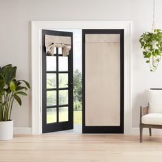 an open door with curtains on it in front of a chair and potted plant