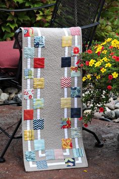 a quilted blanket sitting on top of a chair next to a potted plant