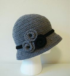 a crocheted gray hat with flowers on the brim, sitting on a white mannequin head