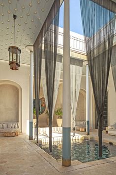 an indoor pool with curtains and lights hanging from it's ceiling, next to a fountain