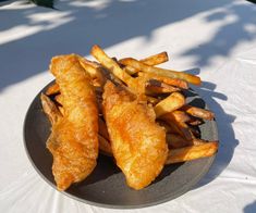 fried fish and french fries on a plate with a white table cloth in the background