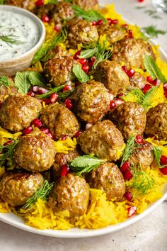 a platter filled with meatballs, rice and garnished with fresh herbs