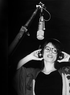 black and white photograph of woman in front of microphone with headphones on her ears