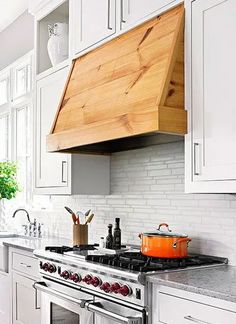 a stove top oven sitting inside of a kitchen under a wooden hood over it's burners