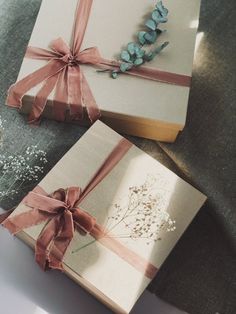 two wrapped gift boxes with ribbons and flowers on them