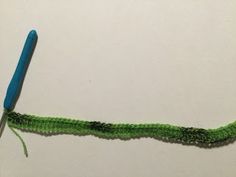 a green piece of yarn with a blue handled crochet hook attached to it