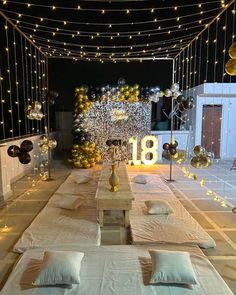 an outdoor party setup with balloons and lights on the ceiling, tables set up in front of them