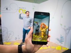 a person holding up a cell phone in front of a wall with cartoon characters on it