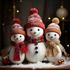 three snowmen wearing hats and scarves are standing in the snow with lights behind them