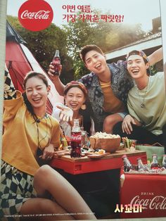 an advertisement for coca - cola is displayed on a table with people sitting around it