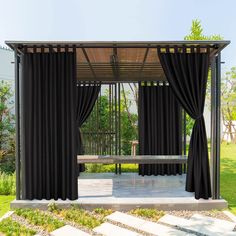 an outdoor gazebo with black curtains and a picnic table in the middle of it