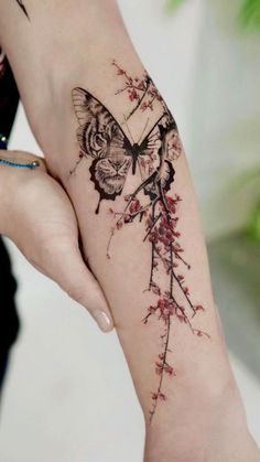 a woman's arm with a butterfly and flower tattoo on the left side of her hand