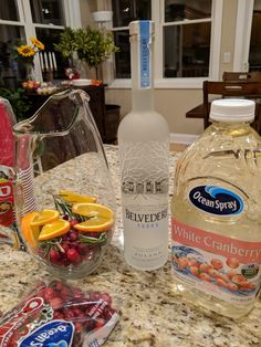 a bottle of white cranberry water next to some fruit and candy on a counter