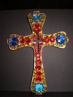 a cross with multicolored stones on it is sitting in front of a black background