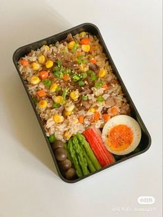 a tray with rice, asparagus, carrots and an egg on it