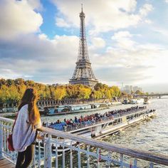 a woman looking at the eiffel tower from across the river in paris, france