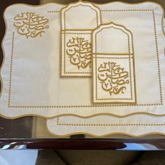 two white and gold embroidered napkins with arabic calligraphy