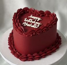 a red heart shaped cake with happy birthday written on it