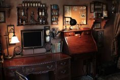 an old fashioned desk and chair in a room with many pictures on the wall above it